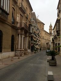 Road by buildings in city against sky