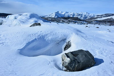 Scenic view of a glacier and snowcapped mountains against a clear sky