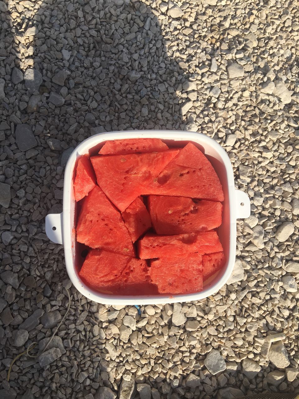 HIGH ANGLE VIEW OF RED AND STONES IN CONTAINER