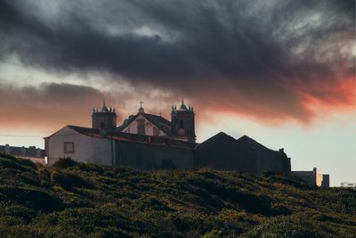 Industrial building against sky at sunset