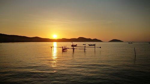 Silhouette people on sea against sky during sunset