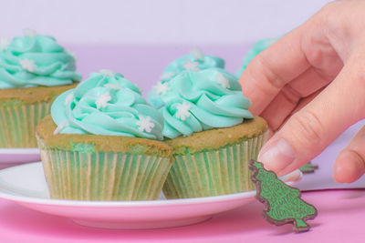 Cropped hand holding cupcake in plate on table