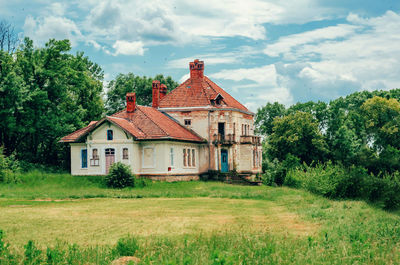 Summer landscape with house and green trees. old abandoned building with tiled roof