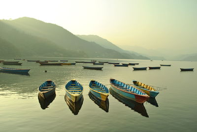 Boats moored in lake against sky