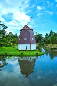 House by lake against sky