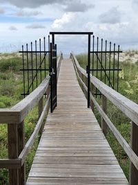 Empty wooden footbridge along plants