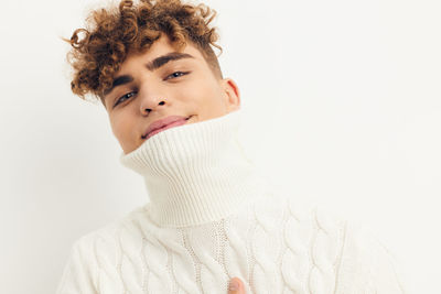Portrait of smiling man with turtleneck against white background