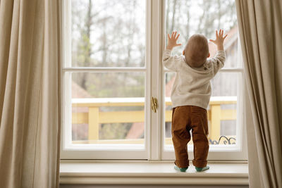 Boy looking through window at home