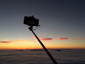 Silhouette smart phone on monopod against sky during sunset