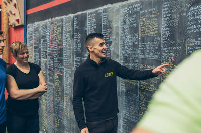 Young man and woman standing against wall