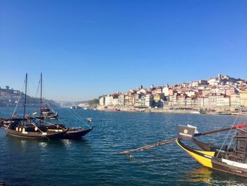 Sailboats moored in sea against clear blue sky