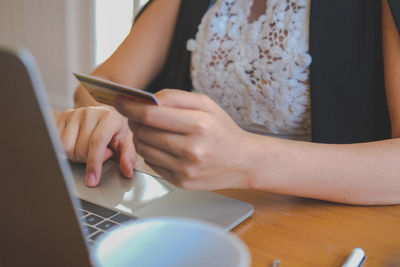 Midsection of woman using laptop on table