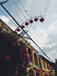 Low angle view of lanterns hanging by building against sky