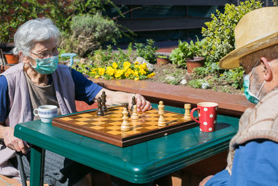 Senior couple playing chess on table while sitting outdoors