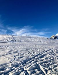 Snow covered landscape against blue sky