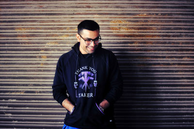 Young man standing against a rusted shutter 