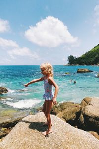 Side view of girl standing on rock at beach