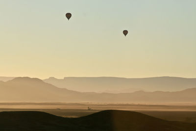 Hot air balloons flying in sky in the sunrise over the namib desert