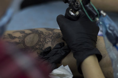 Cropped image of tattoo artist working on customer leg