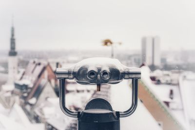 Close-up of coin-operated binoculars against cityscape