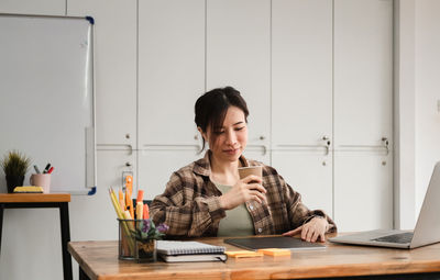 Young man using mobile phone while sitting on table