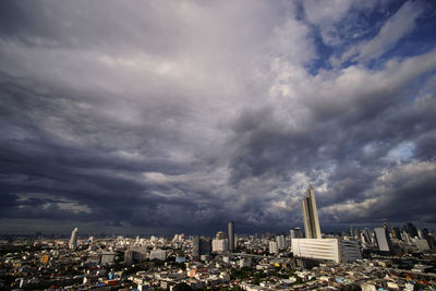 Aerial view of buildings in city against cloudy sky