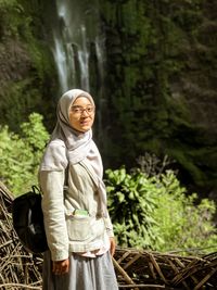 Portrait of woman standing against waterfall
