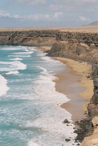 Scenic view of ocean and cliffs against sky