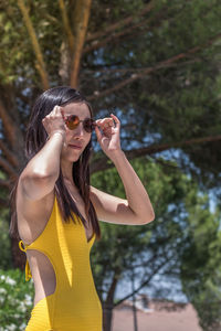 Asian woman wearing sunglasses with a yellow bathing suit