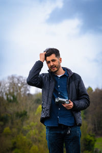 Young man standing against sky