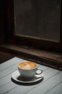 Latte art coffee on wooden table in coffee shop