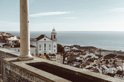 Buildings by sea against sky