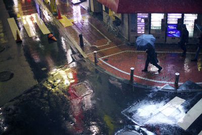 Man walking on wet street in city at night