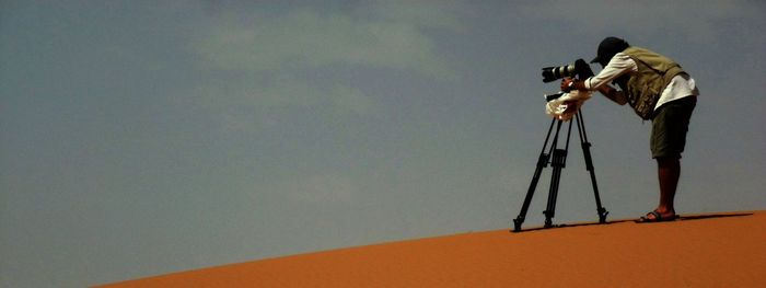 Man holding umbrella against sky
