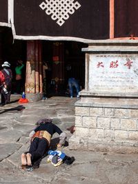 People sitting on street against building