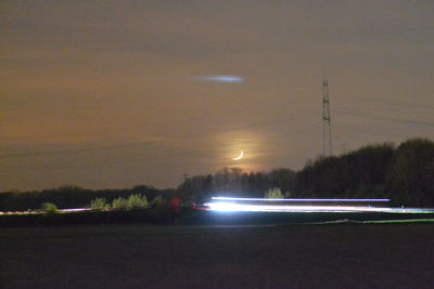 Cars on illuminated road against sky at night
