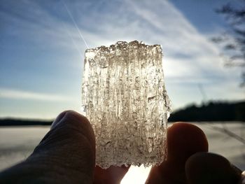Cropped image of person holding ice against sky