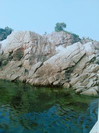 Rock formations in water against sky