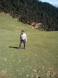 Full length of man standing on grassy hill during sunny day