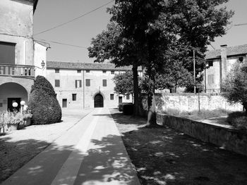 Street amidst trees and buildings against sky