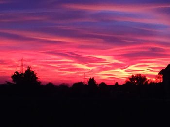 Silhouette trees on landscape against sky at sunset