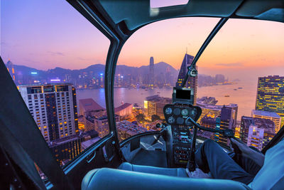 Illuminated cityscape against sky during sunset seen through helicopter