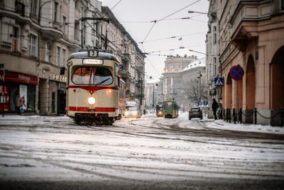 Trams moving on snow covered street in city