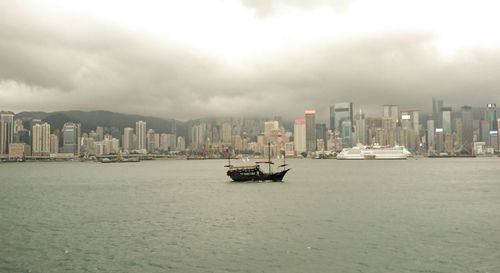 City at waterfront against cloudy sky