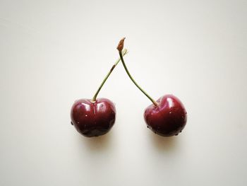 Close-up of red cherries over white background