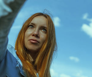 Portrait of a beautiful young woman against sky