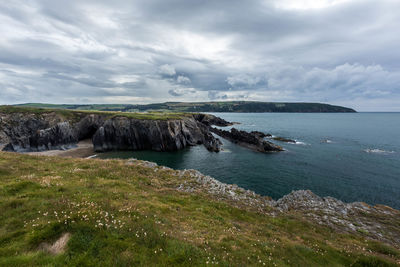 Scenic view of sea and landscape against cloudy sky