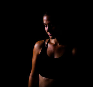 Young woman standing against black background