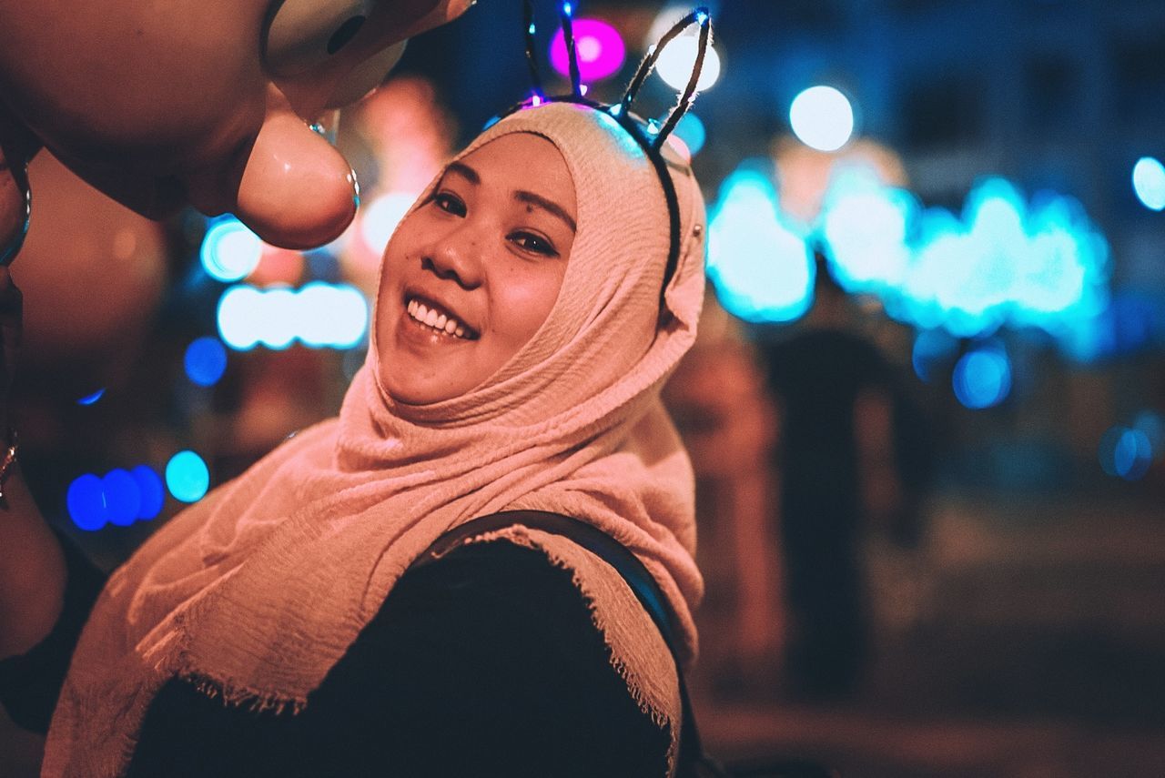 focus on foreground, real people, leisure activity, lifestyles, night, smiling, illuminated, women, emotion, adult, portrait, happiness, young women, headshot, young adult, looking at camera, incidental people, nightlife