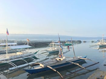 Boats moored at harbor against sky